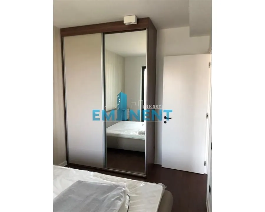 Bedroom with a large fitted wardrobe with sliding doors and a mirror.