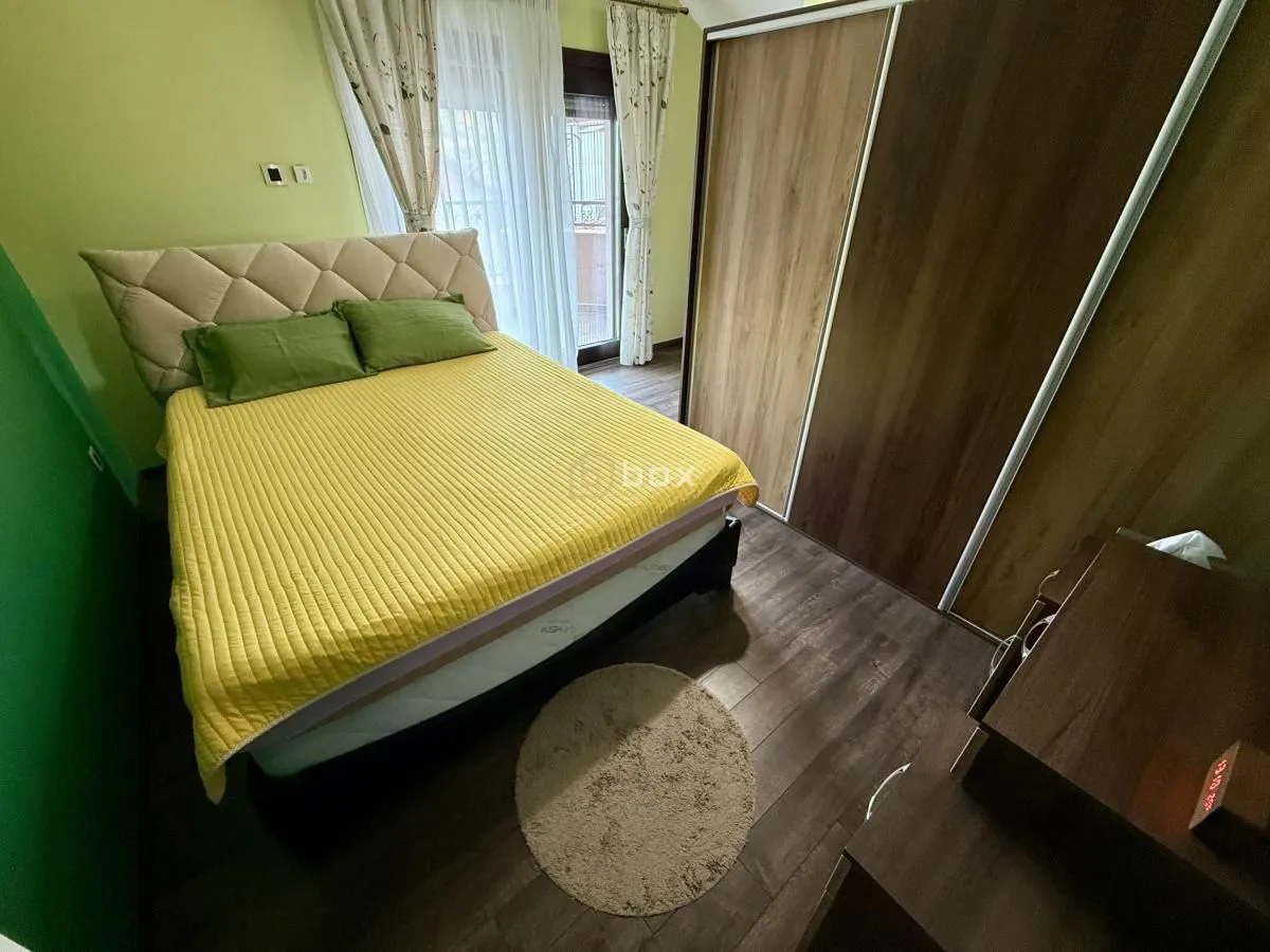 Nameštena spavaća soba sa bračnim krevetom, ormarom i izlazom na terasu.