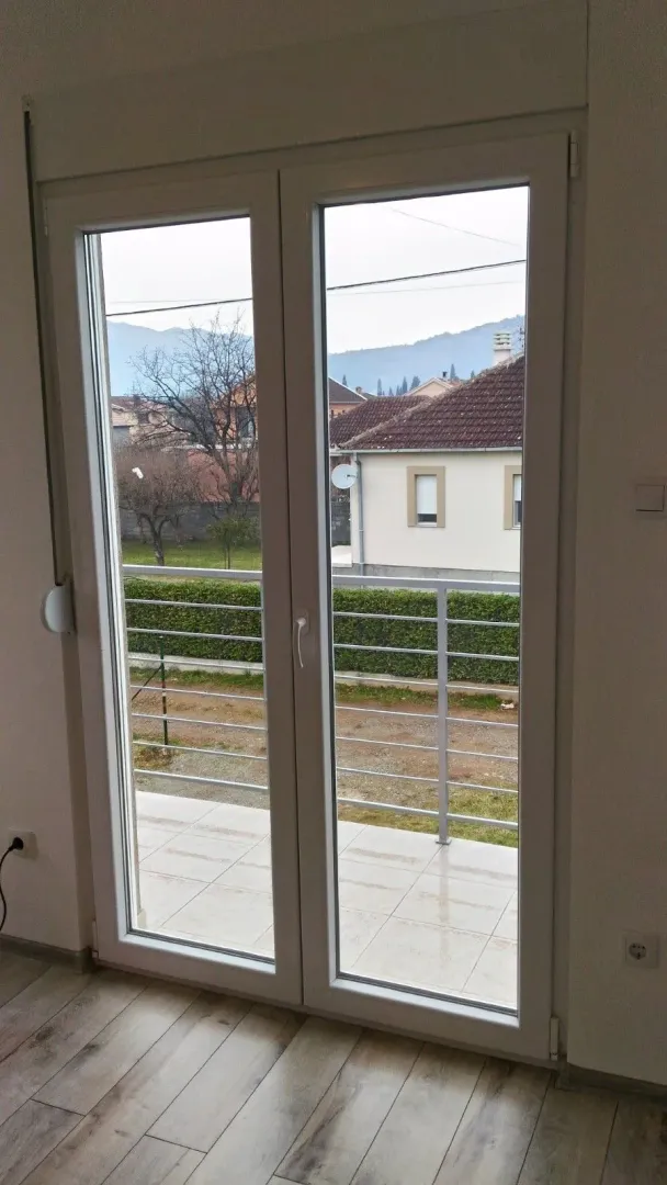View through balcony doors onto a tiled terrace and yard.