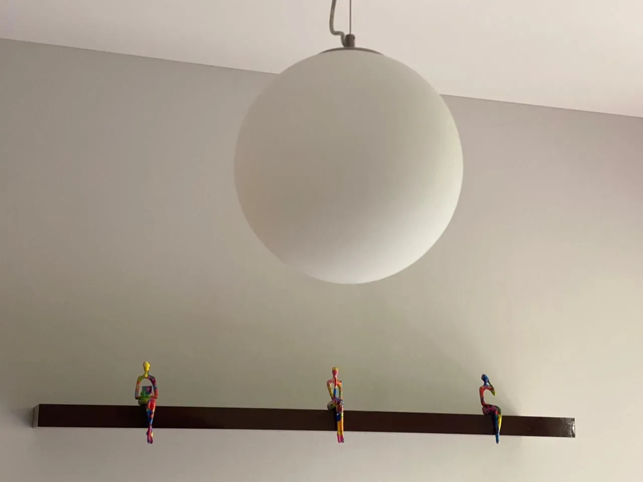 Detalj enterijera sa dekorativnim figurama na polici i visećom lampom.
