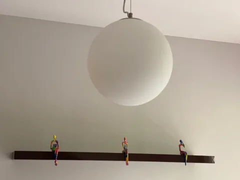 Detalj enterijera sa dekorativnim figurama na polici i visećom lampom. - image 10