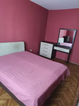Spavaća soba sa rozim zidovima, bračnim krevetom i komodom sa ogledalom. - image 5