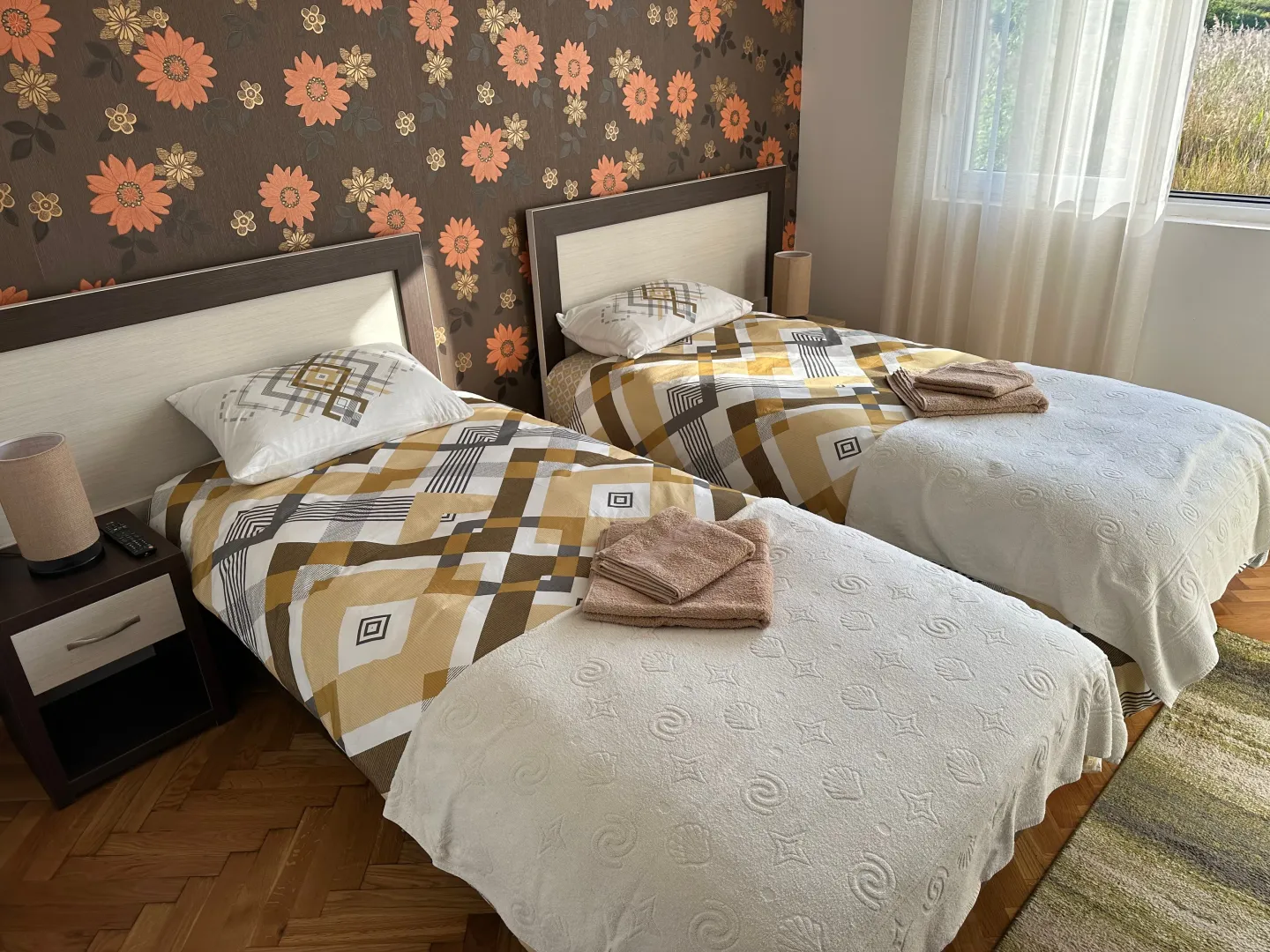 Spavaća soba sa dva odvojena kreveta i noćnim stočićima.