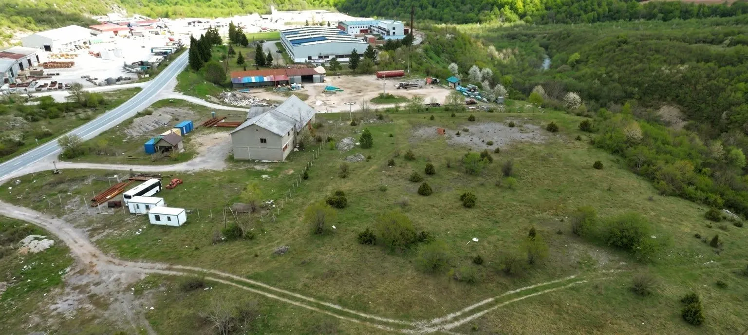 Pogled iz vazduha na zemljište i okolni pejzaž sa putem i objektima.