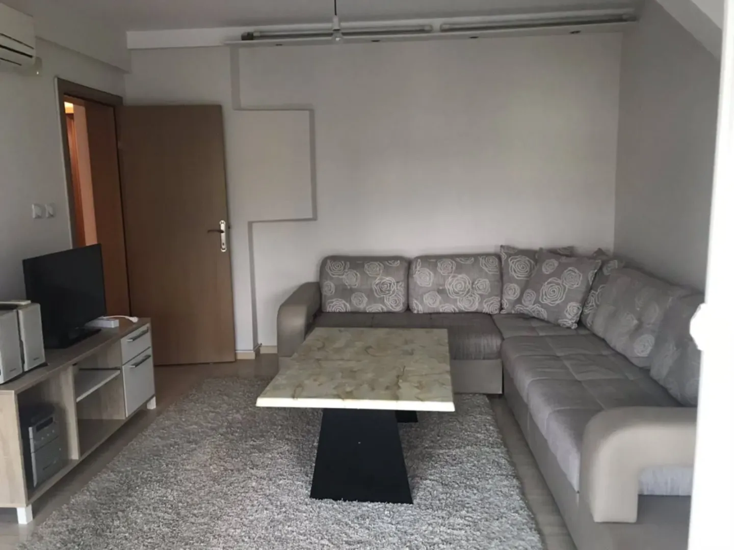 Dnevni boravak sa garniturom, stočićem i televizorom.