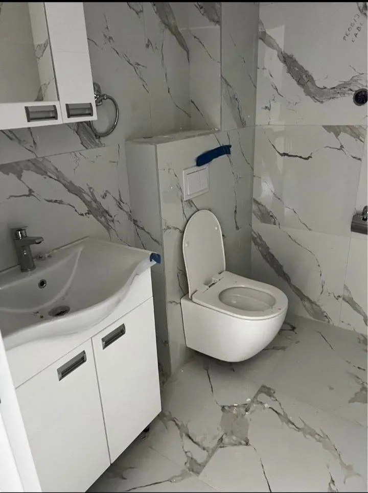 Modern bathroom with white sanitary ware and marble tiles.