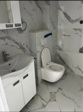 Modern bathroom with white sanitary ware and marble tiles. - image 7