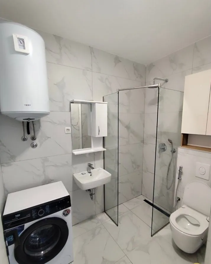 Moderne opremljeno kupatilo sa tuš kabinom, umivaonikom, veš mašinom i toaletom.