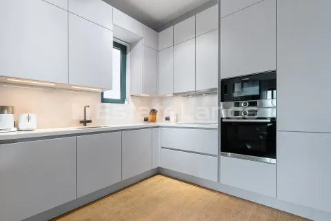 Moderna bijela kuhinja sa ugradnim aparatima i drvenim podom. - image 9