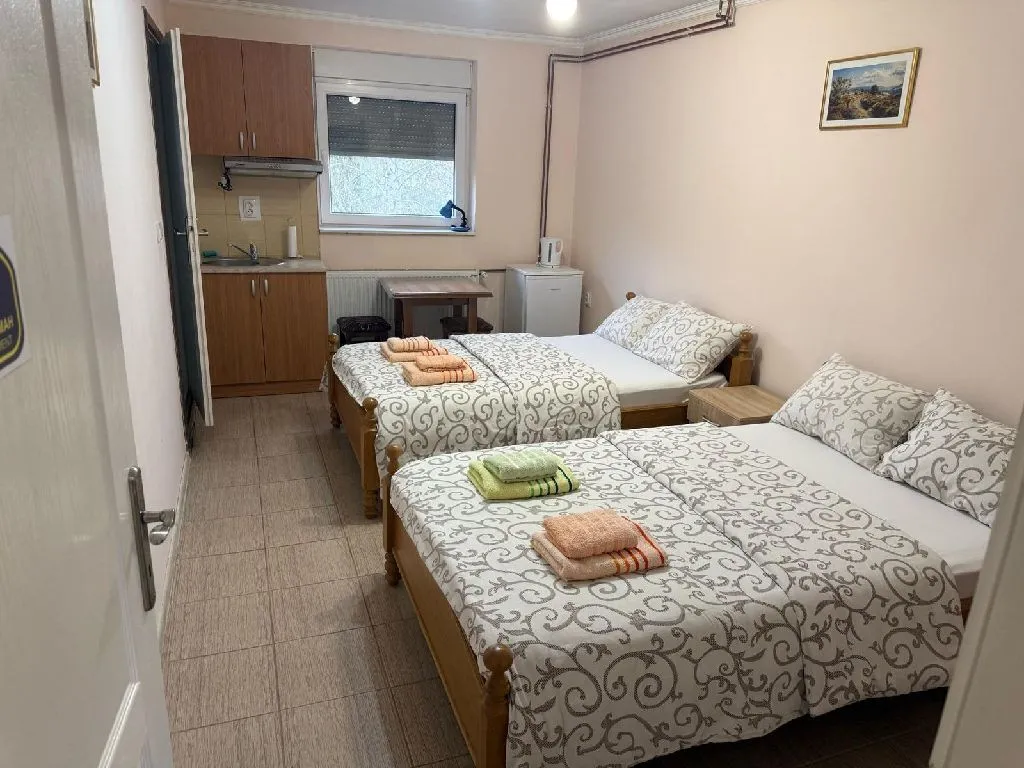 Spavaća soba sa dva kreveta i manjom kuhinjom u uglu.
