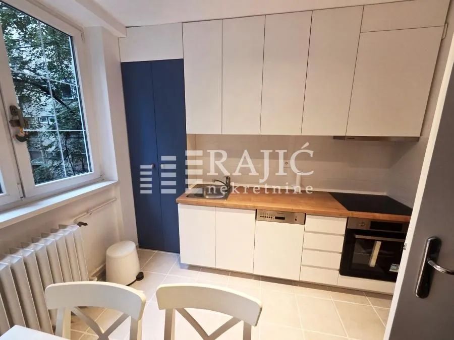 Small bright kitchen with white cabinets and wooden countertops.