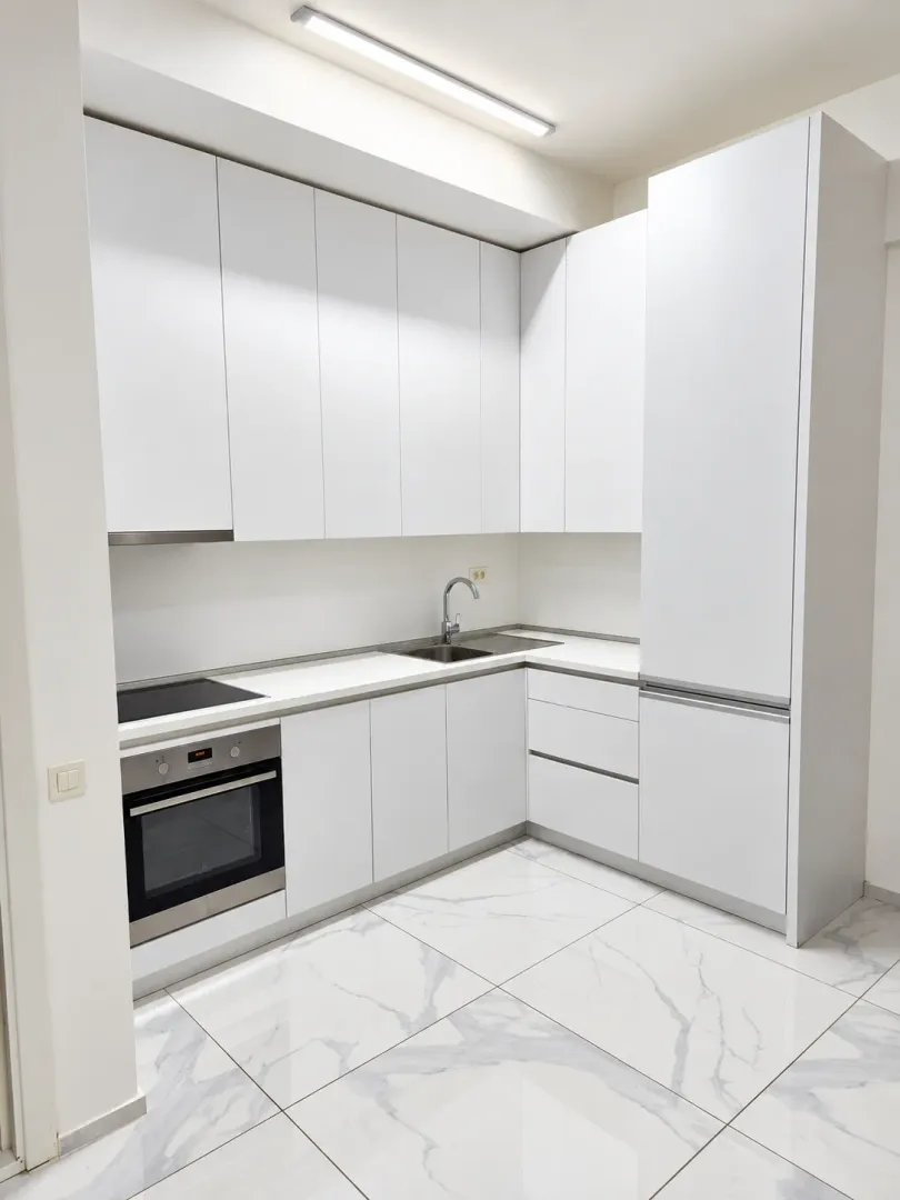 Modern white kitchen with built-in oven and hob.