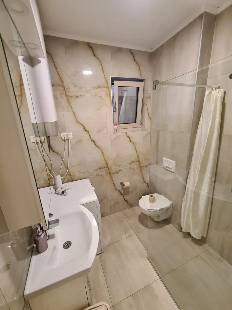 Moderne kupatilo sa umivaonikom, tuš kabinom i WC šoljom.