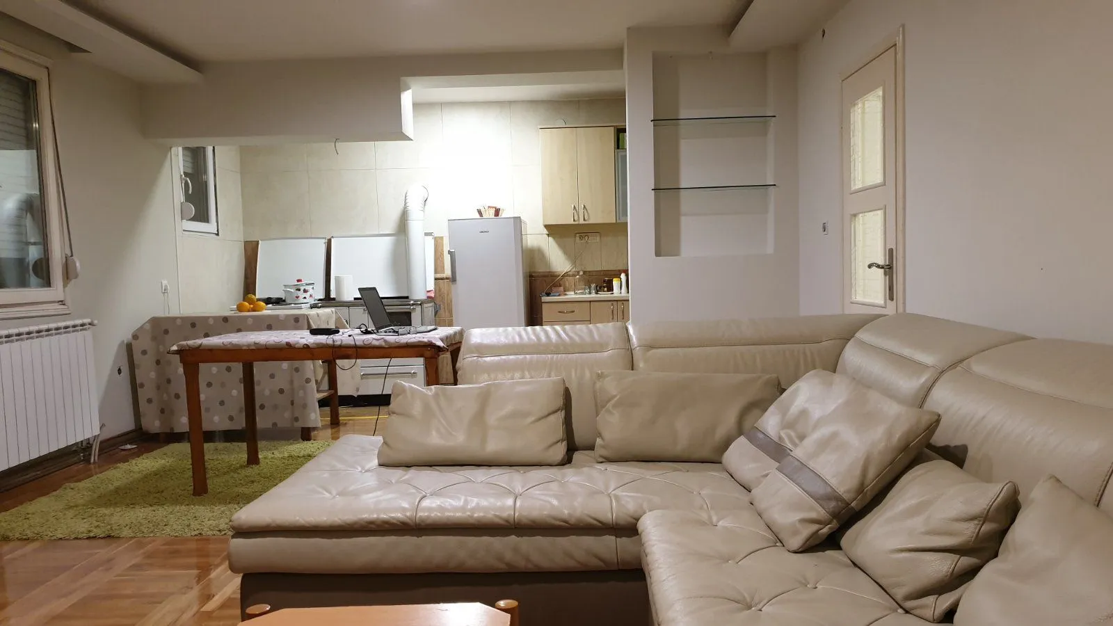 Living room with a leather sofa and kitchen in the background.