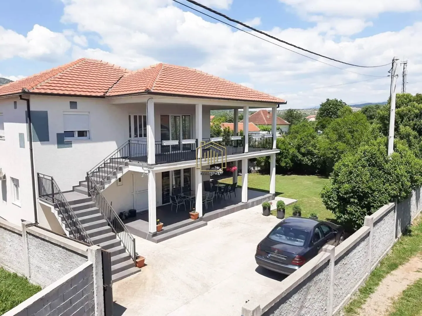 Pogled iz vazduha na dvospratnu kuću sa dvorištem i terasama.