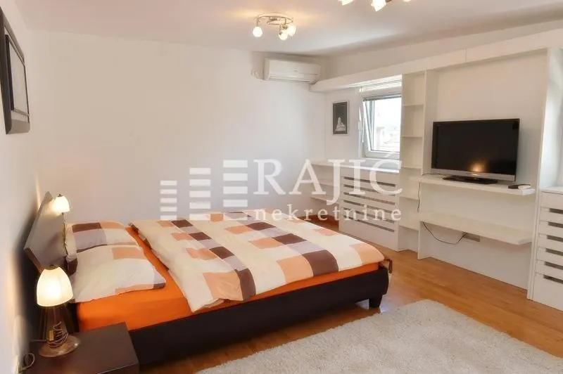 Furnished bedroom with a double bed, TV unit, and white furniture.