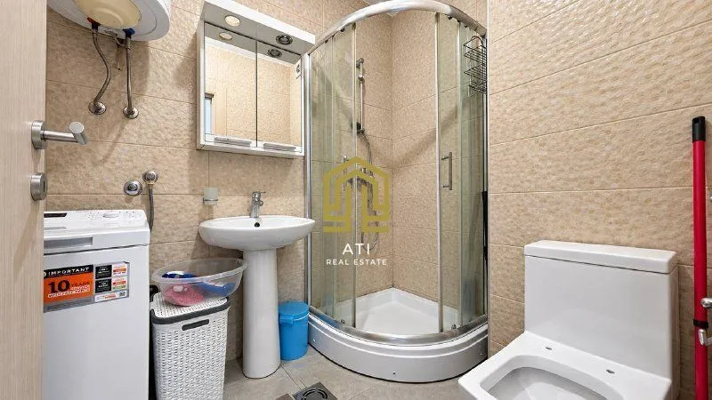 Bathroom equipped with a shower cabin, sink, toilet, and washing machine.