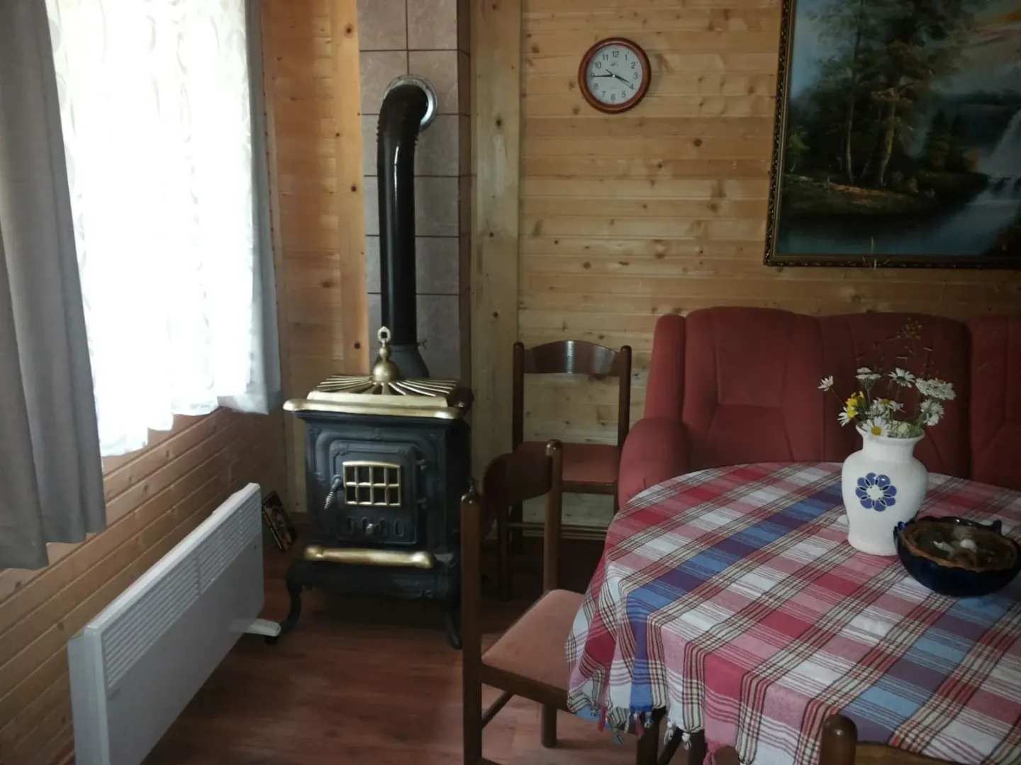 Dnevna soba u drvenoj kući sa peći na drva, stolom i kaučem.