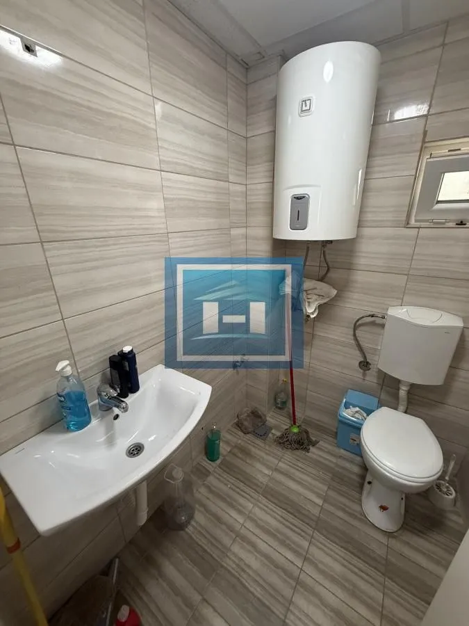 Smaller bathroom with a washbasin, toilet, and water heater.