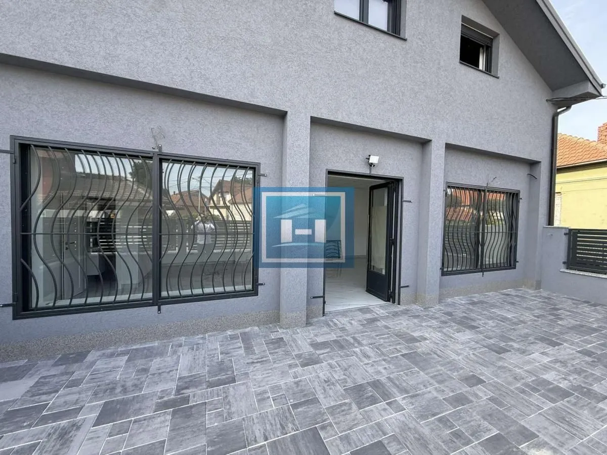 View of the paved courtyard and the facade of the house with the entrance.