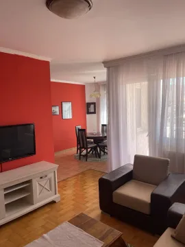 Bright living room featuring a bold red accent wall and a dining area in the background. - image 16