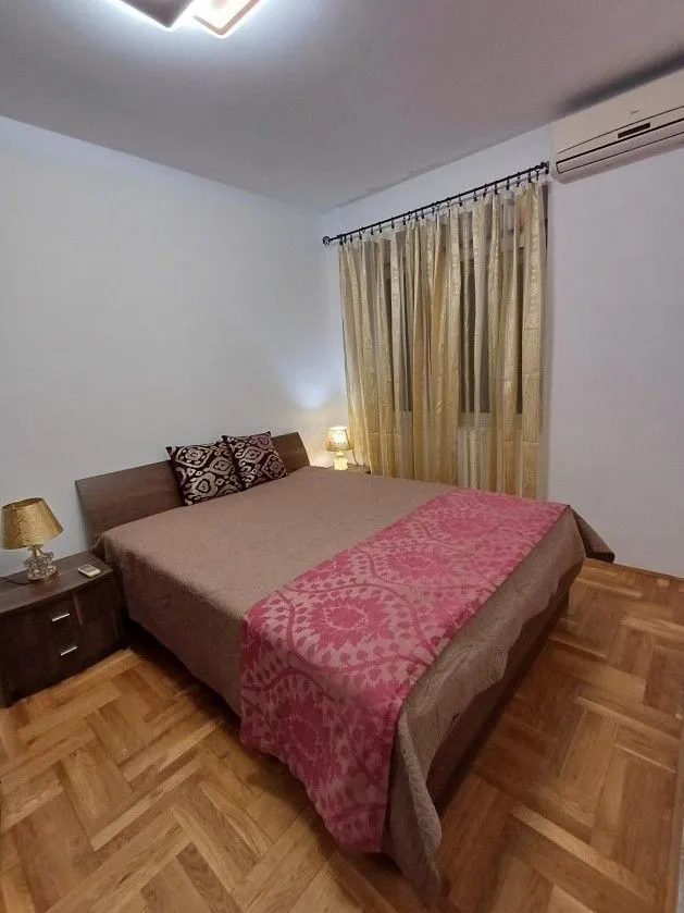 Spavaća soba sa bračnim krevetom i noćnim stočićima.