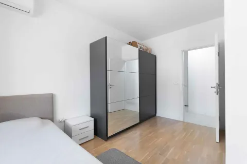 Bright bedroom with a bed, large mirrored wardrobe, and parquet flooring. - image 23
