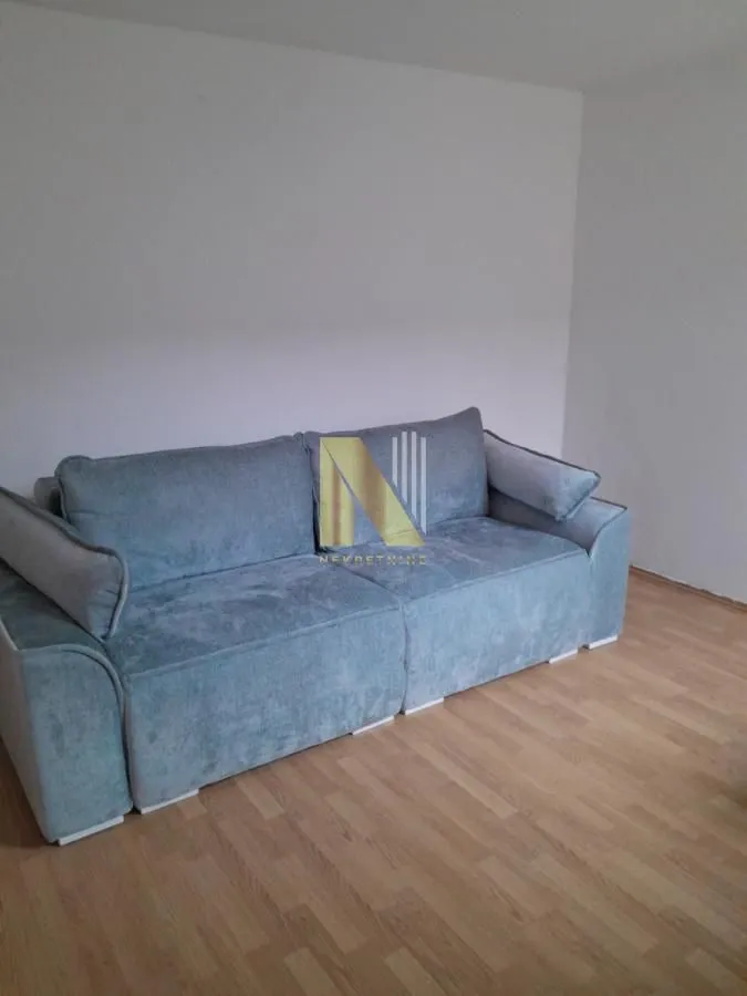 Living room with a blue sofa and wooden flooring.