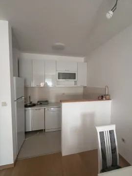 Mala kuhinja sa bijelim elementima, frižiderom i malim šankom. - image 3