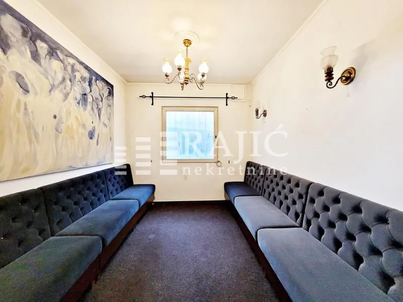 Living room with upholstered benches and a large artwork on the wall.
