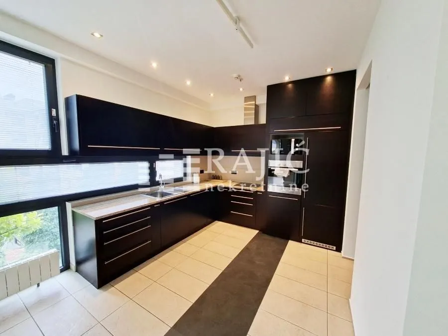 Modern kitchen with dark cabinetry and built-in appliances.