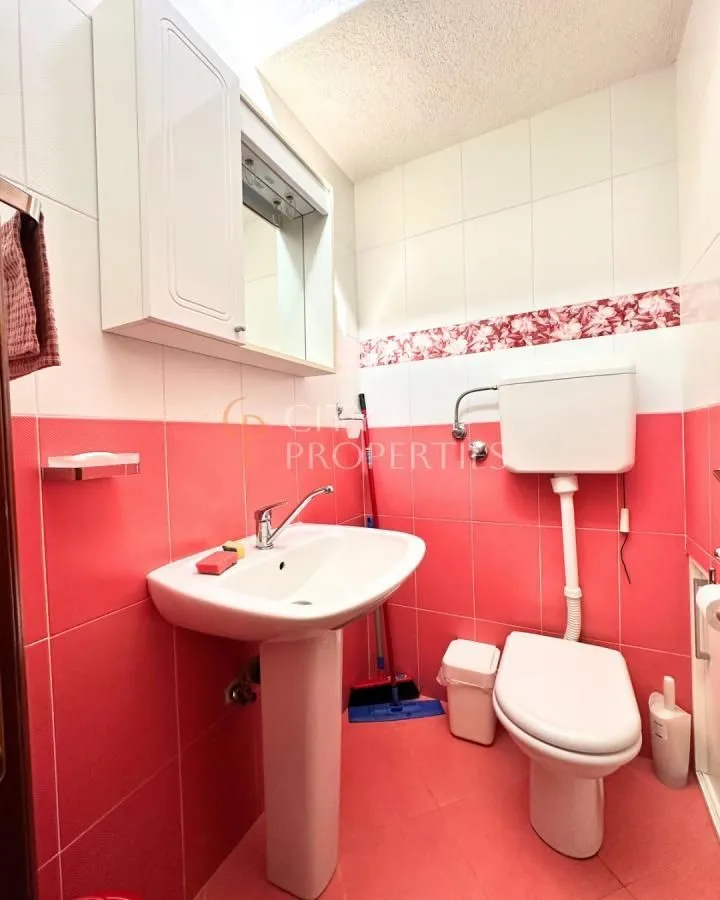 Manje kupatilo sa lavaboom, WC šoljom i zidnim ormarićem sa ogledalom.