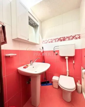 Manje kupatilo sa lavaboom, WC šoljom i zidnim ormarićem sa ogledalom. - image 8