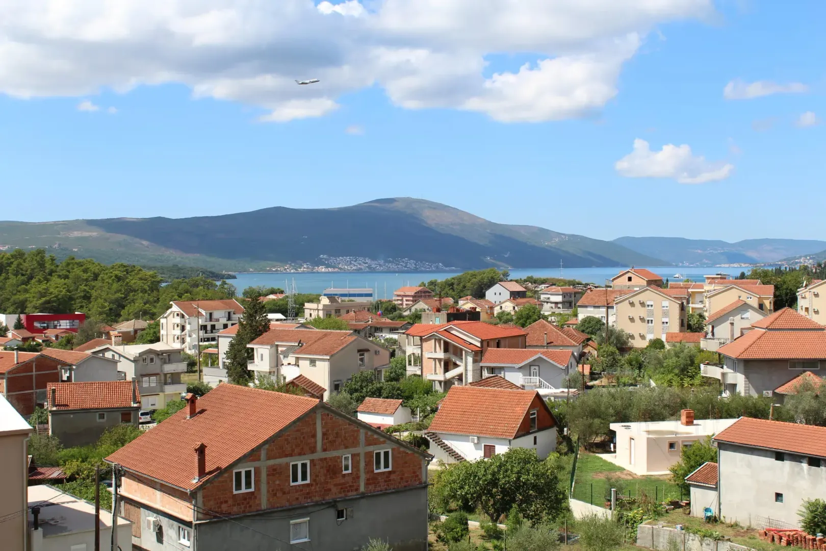 Pogled sa nekretnine na okolno naselje, more i planine u daljini.