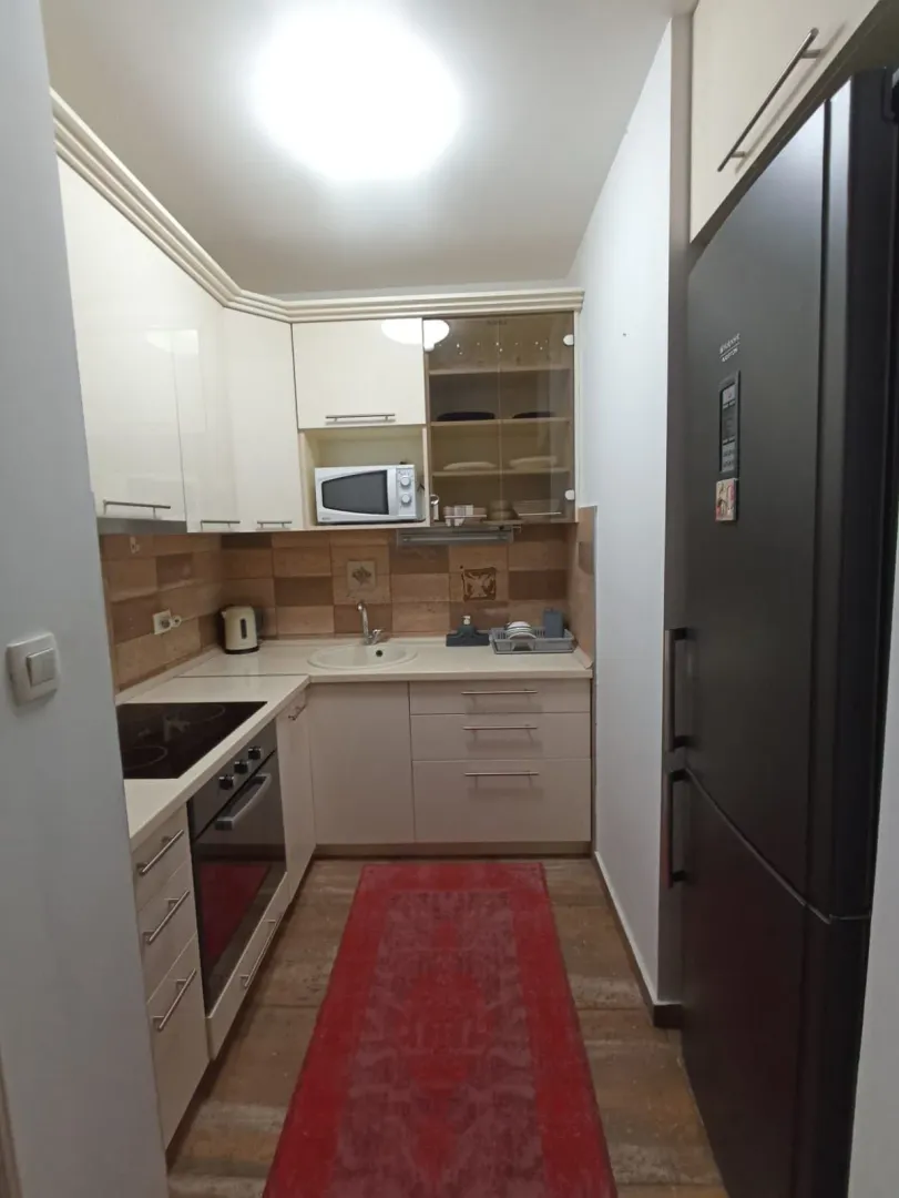 Smaller equipped kitchen with white cabinets and a black refrigerator.