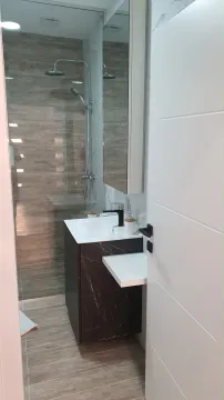 Modern bathroom equipped with a shower cabin and washbasin. - image 7
