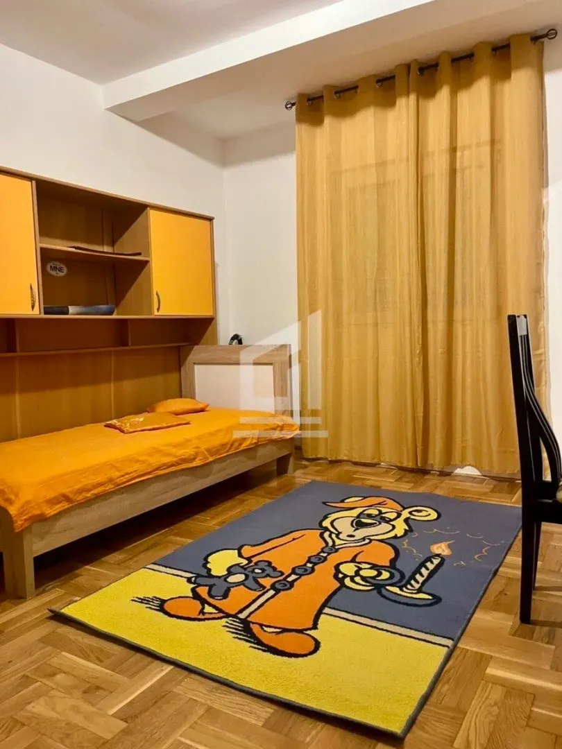 Children's bedroom with a bed, wardrobe, and a cartoon character rug.