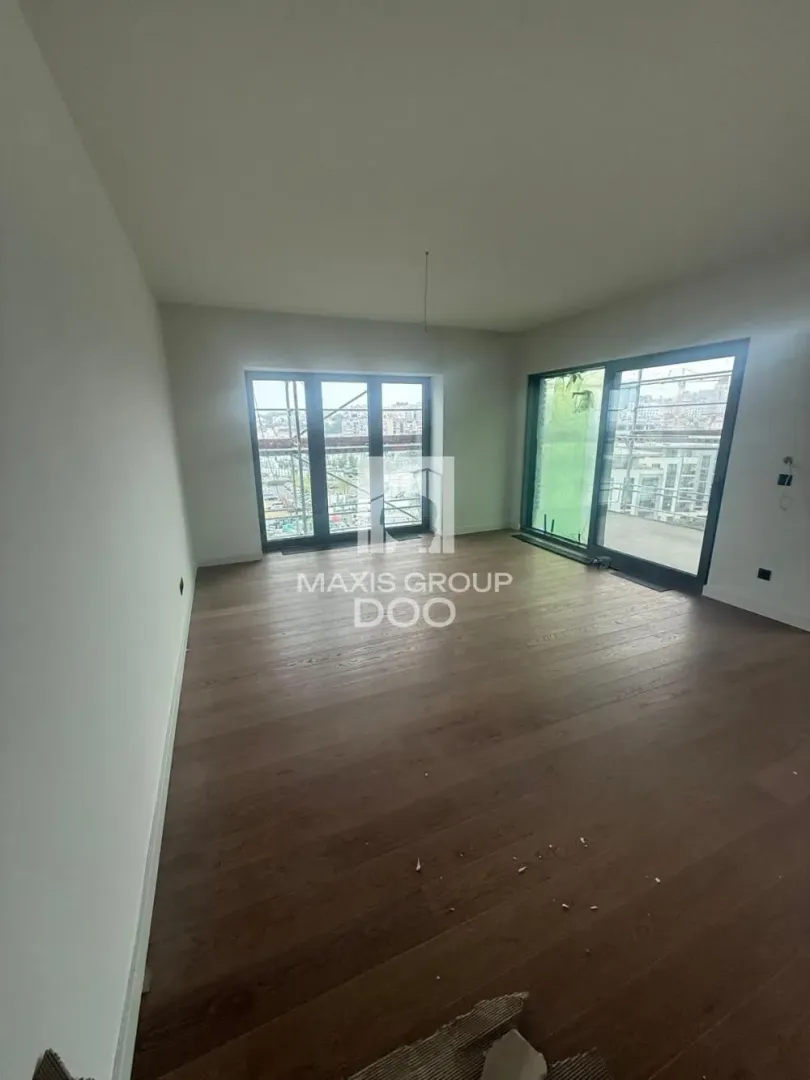Empty unfurnished room with wooden flooring and large windows.