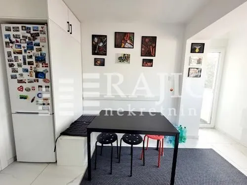 Dining area with a black table and chairs, connected to the kitchen.