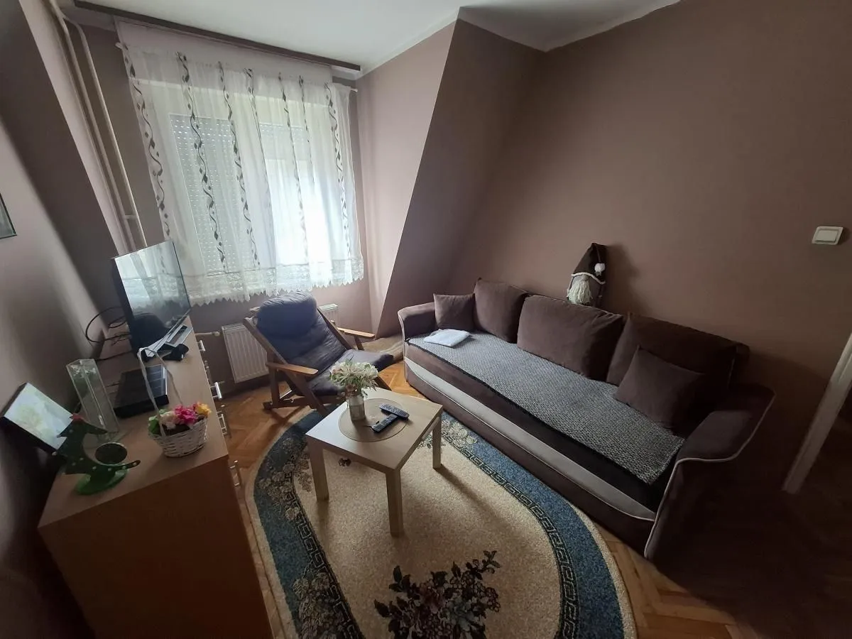 Dnevna soba sa garniturom za sedenje, stočićem i televizorom.