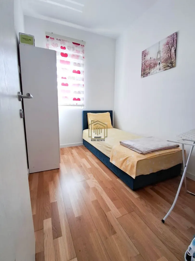 Manja spavaća soba sa krevetom za jednu osobu, garderoberom i drvenim podom.