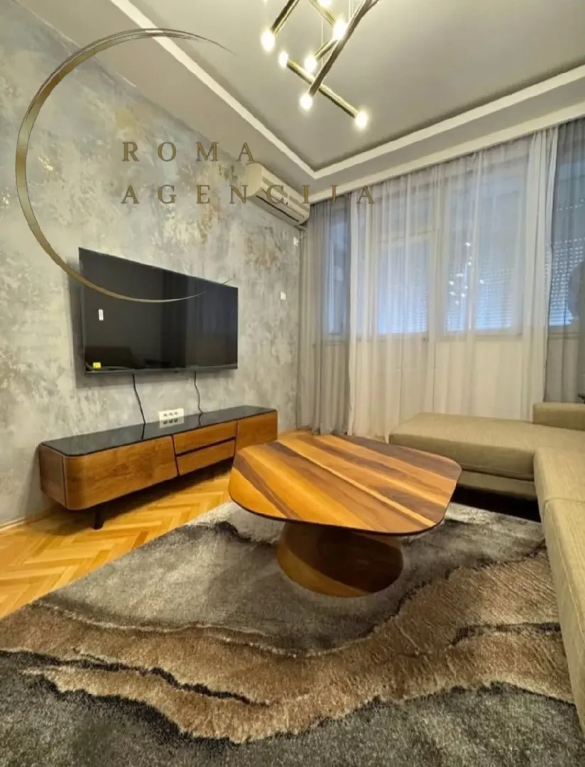 Living room with a sofa, TV, and decorative wall.