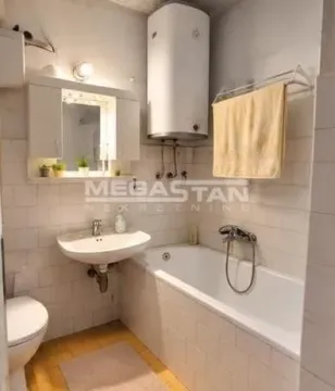 Smaller bathroom equipped with a bathtub, washbasin, toilet, and water heater. - image 5