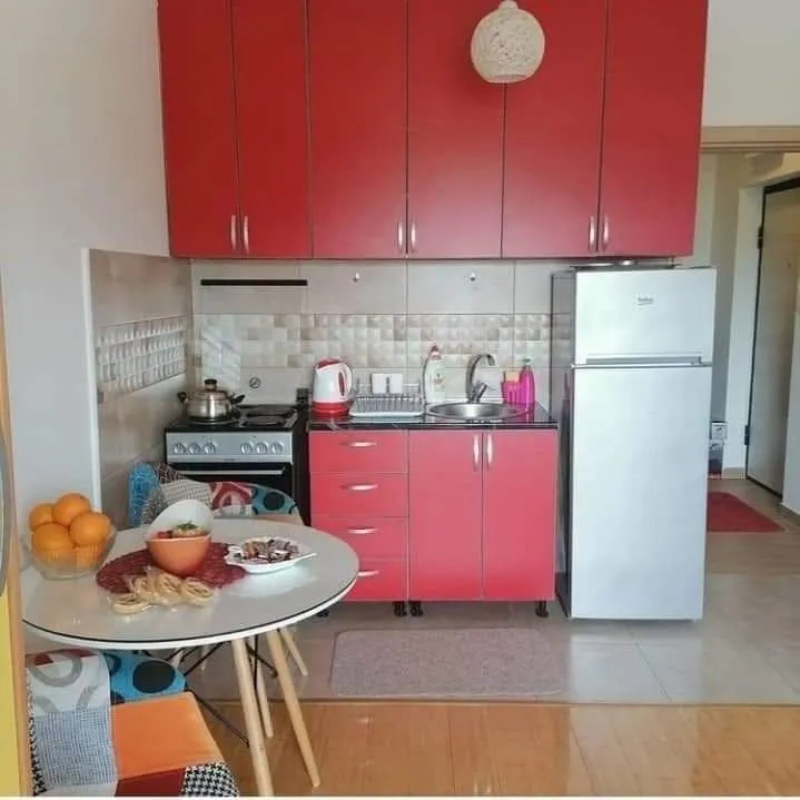 A kitchen with red cabinets and a small round table.