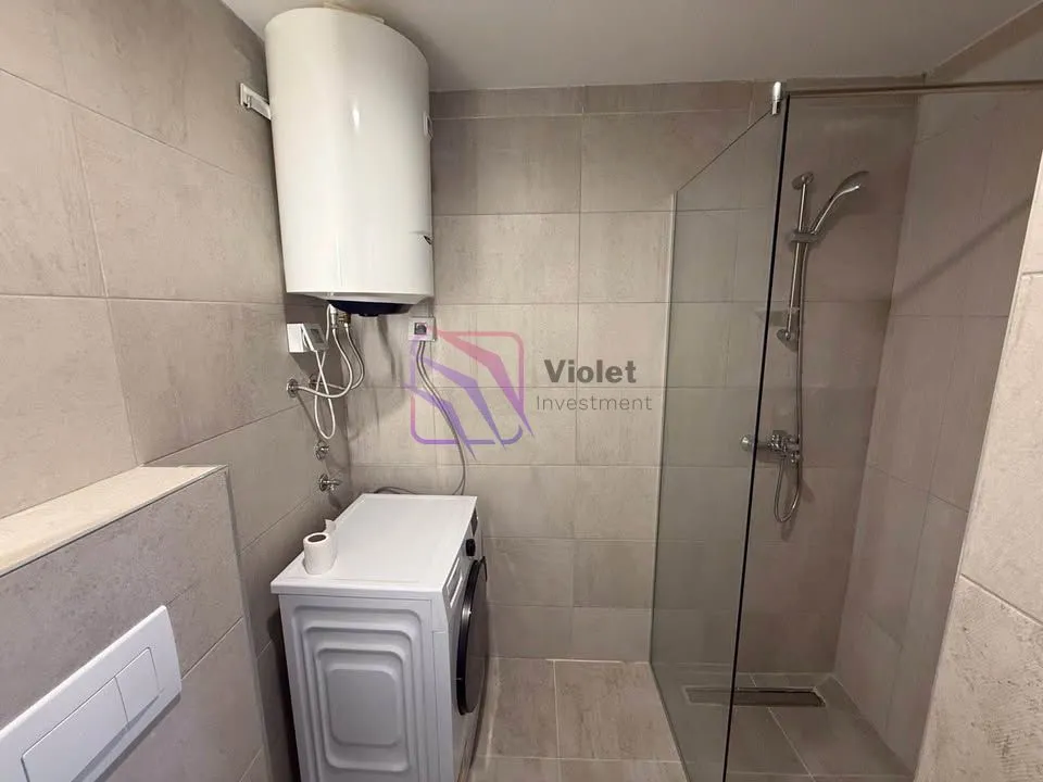 Bathroom equipped with a shower cabin, water heater, and washing machine.