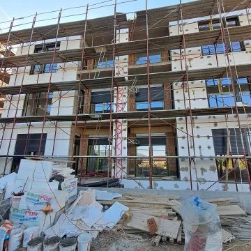 Fasada zgrade u izgradnji sa postavljenim skelama i građevinskim materijalom. - image 8