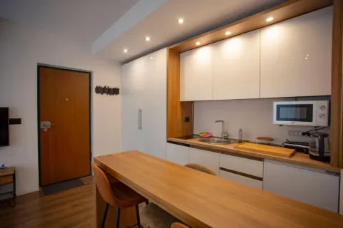 Modern kitchen with white cabinets, wooden details, and a breakfast bar. - image 4