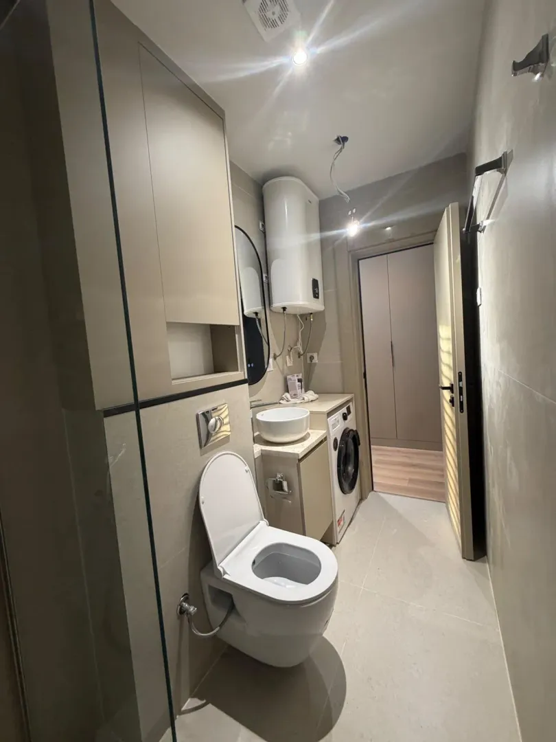 Moderno opremljeno kupatilo sa veš mašinom i tuš kabinom.