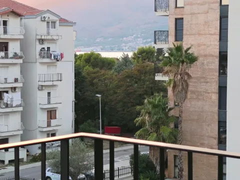 View from the terrace towards the surrounding buildings, greenery, and the sea in the distance. - image 10