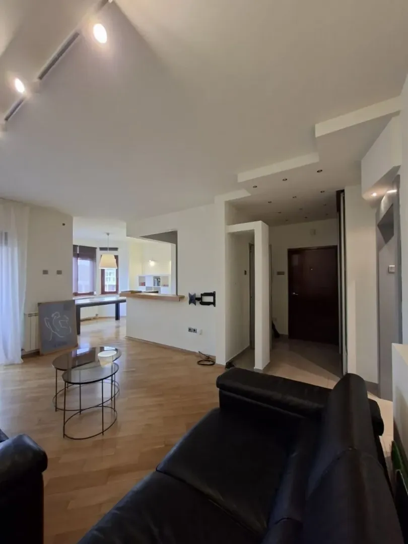 Living room with a sofa and a view towards the kitchen and the entrance door.
